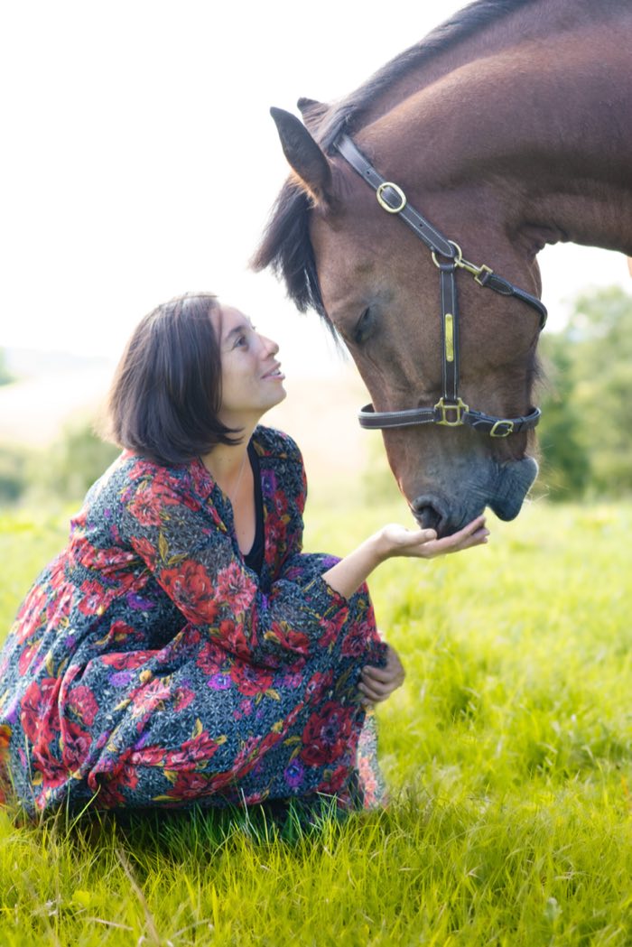 Complicité entre une cavalière et son cheval bai, au pré
