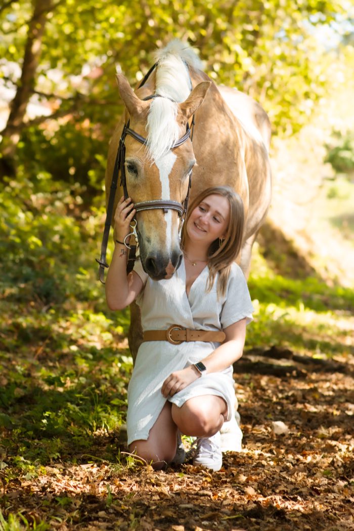Cavalière et son cheval sur un chemin bordé d’arbres