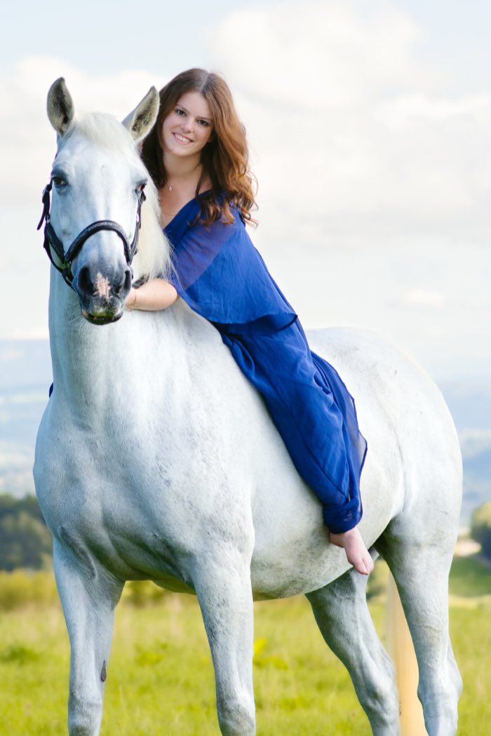 Cavalière en robe bleue montée sur sa jument grise