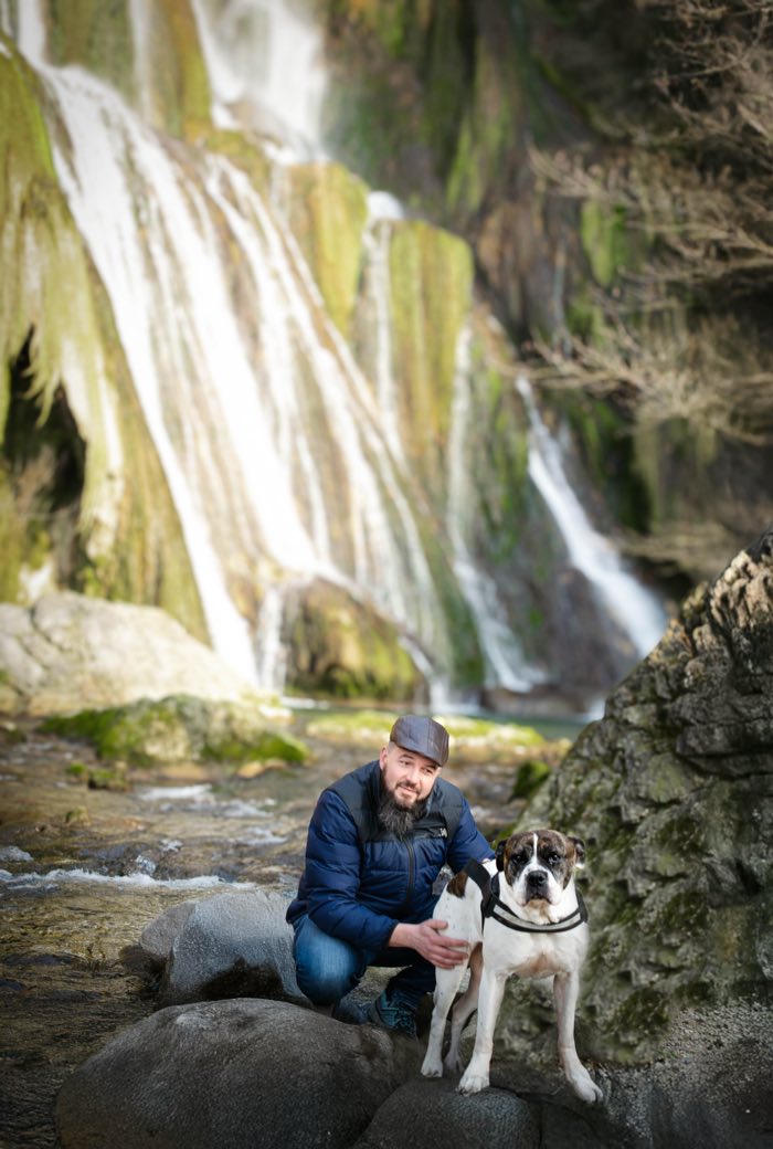 Un couple et son chien au pied d’une cascade